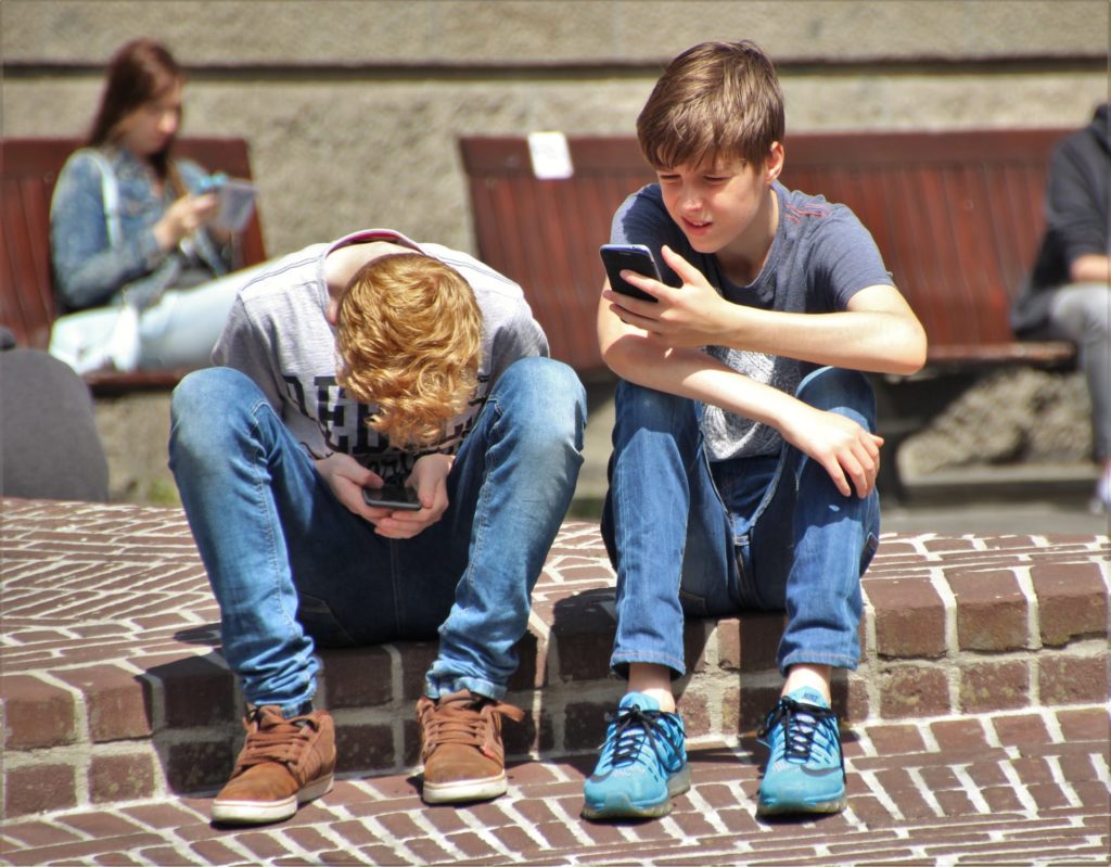 Kids-on-phones Two teenage boys with smartphones - a family traveling with kids has unique mobile internet challenges