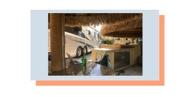 las-vegas-reundancy Photo of a Class A RV with a laptop on a table in the foreground taken from a chair under a tropical awning set outdoors